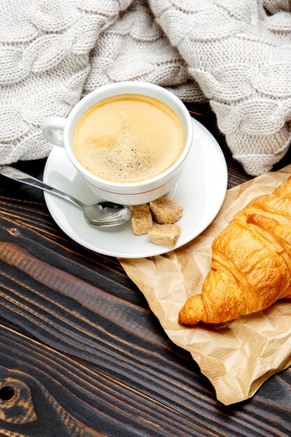 Tazza di caffè e croissant su fondo di legno