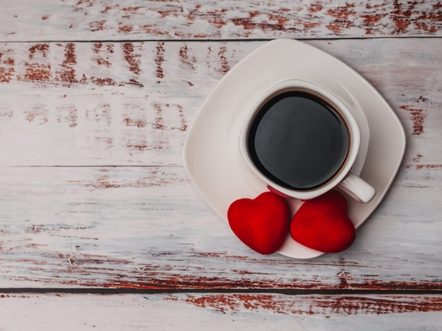 Tazza di caffè e cuori sulla tavola di legno. Concetto di mattina Colazione a San Valentino