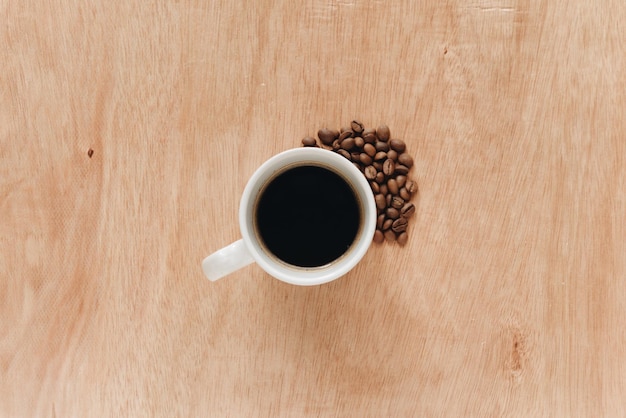 Tazza di caffè e fagioli su un fondo di legno