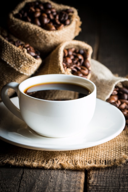 Tazza di caffè e fagioli su uno sfondo rustico.