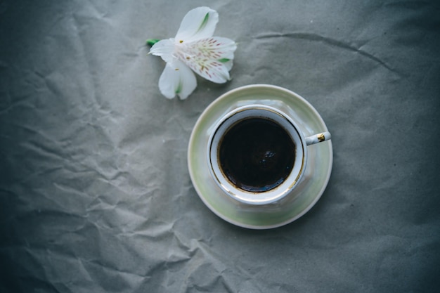 tazza di caffè e fiore bianco su sfondo grigio