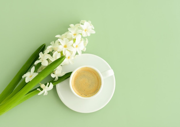 Tazza di caffè e fiore di primavera sul tavolo verde vista dall'alto fiori di caffè espresso su sfondo verde pastello