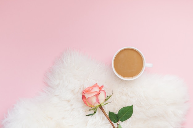 Tazza di caffè e fiore rosa sul rosa