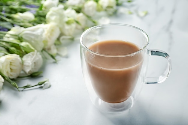 Tazza di caffè e fiori di vetro sul tavolo