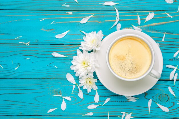 Tazza di caffè e fiori sulla tavola di legno leggera