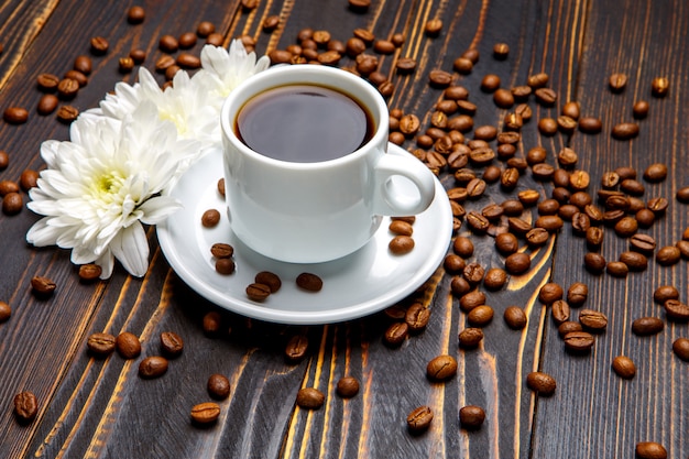 Tazza di caffè e fiori sulla tavola di legno scura