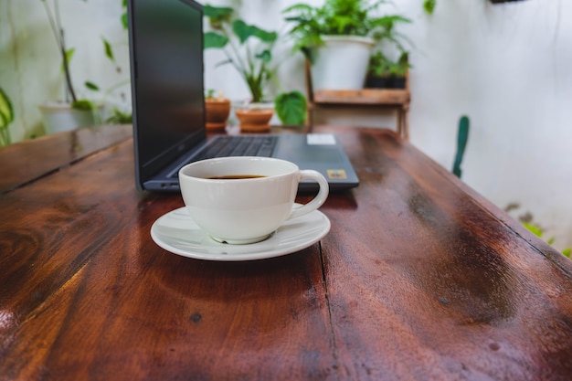 Tazza di caffè e laptop su un tavolo di legno in giardino
