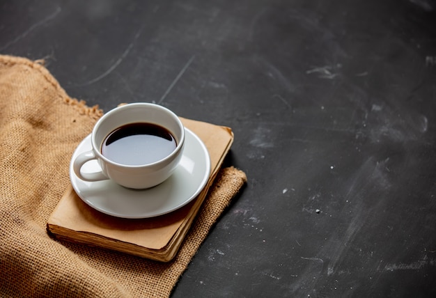 Tazza di caffè e libro d'annata su una tavola scura