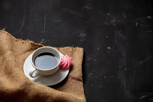 Tazza di caffè e meringa bianche su fondo scuro