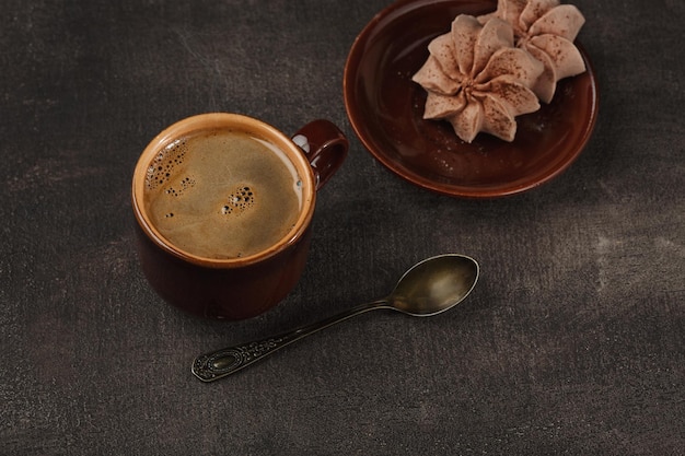 Tazza di caffè e meringa sul tavolo. Sfondo scuro.