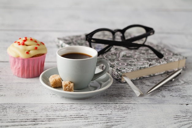 Tazza di caffè e muffin sulla tavola dell'ufficio all'inizio del giorno lavorativo