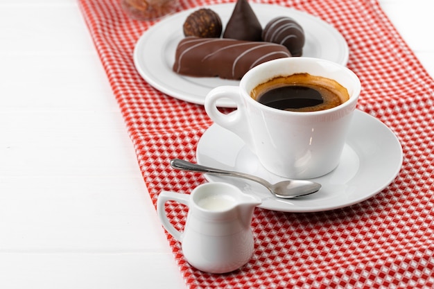 Tazza di caffè e piattino con dolci al cioccolato sulla tavola di legno si chiuda