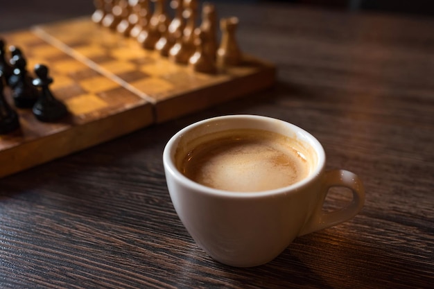 Tazza di caffè e scacchiera in una prospettiva su un tavolo di legno