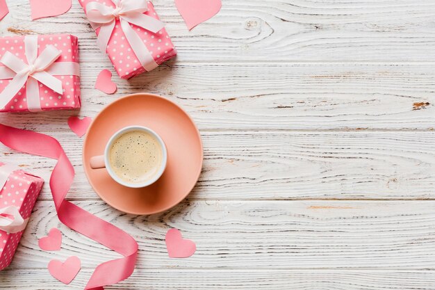 Tazza di caffè e scatola regalo su sfondo colorato Composizione piana concetto di vacanza