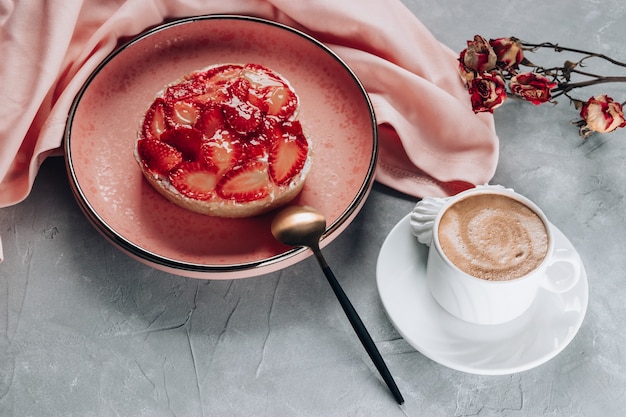 Tazza di caffè e torta con fragole sul tavolo grigio