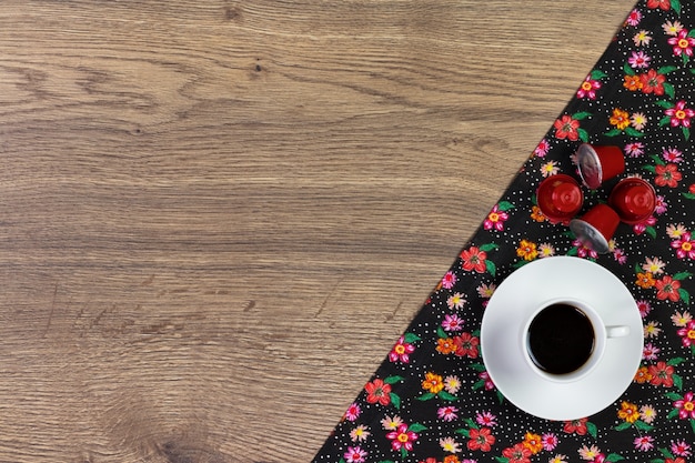 Tazza di caffè e tovagliolo di stoffa floreale su fondo di legno.