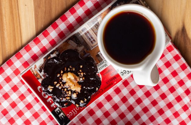 Tazza di caffè e una caramella al cioccolato sotto il tavolo di legno