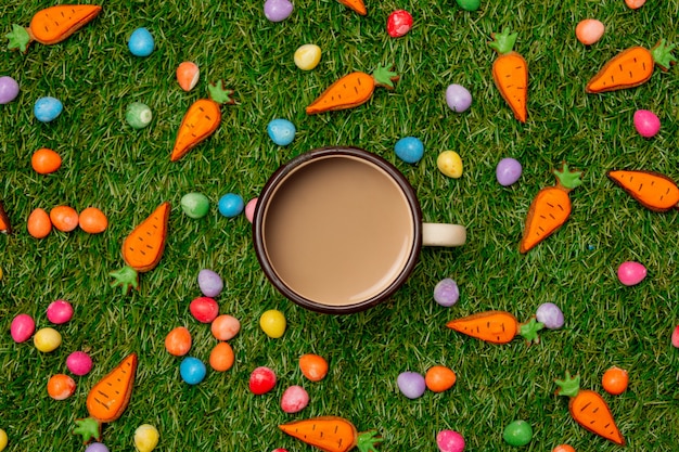 Tazza di caffè e uova di cioccolato di Pasqua con le carote del biscotto sull'erba verde