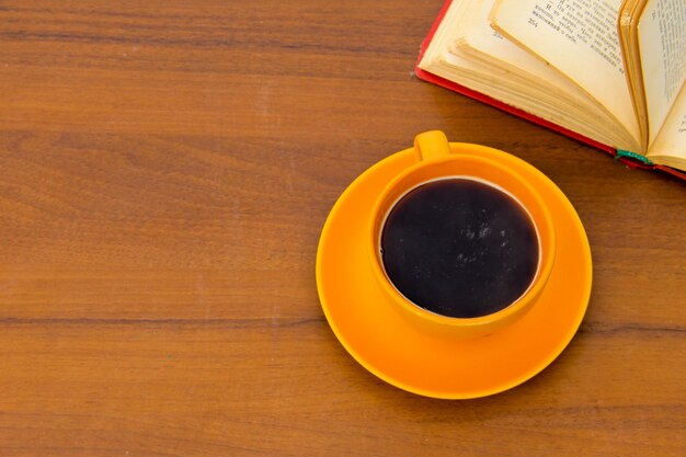 Tazza di caffè e vecchio libro sulla scrivania in legno