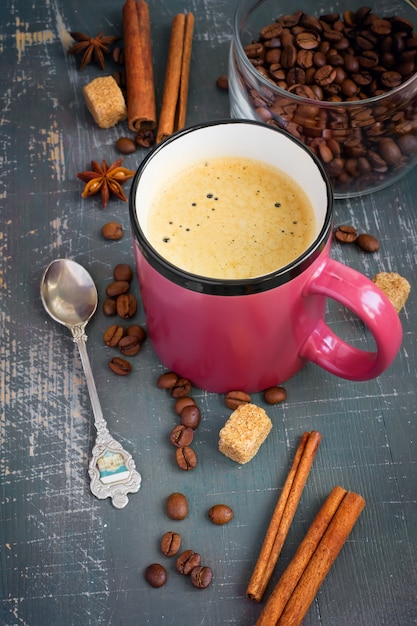 Tazza di caffè espresso con bastoncini di cannella e chicchi di caffè