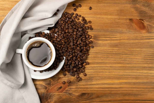 Tazza di caffè espresso e chicchi di caffè caldi sulla vista superiore del fondo di legno marrone della tavola.