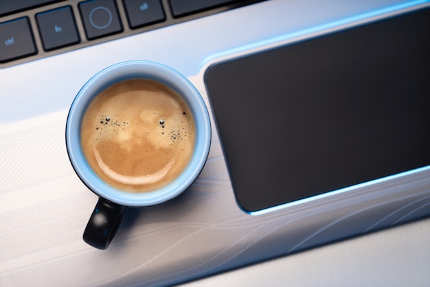 tazza di caffè espresso si trova su un computer portatile.