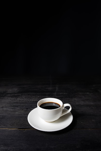 Tazza di caffè espresso sul tavolo nero vintage, vista frontale. Caffè in tazza bianca su superficie scura con piacevole vecchia struttura di legno