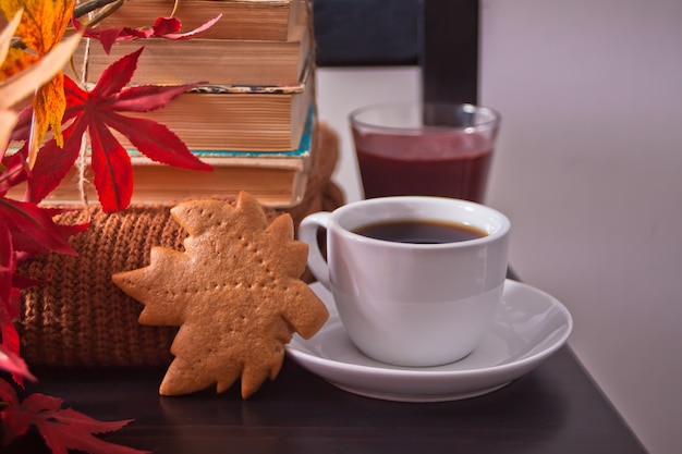 Tazza di caffè, foglie di autunno, biscotti. sedia nera di legno dei vecchi libri. Vendemmia autunnale. Concetto di autunno.