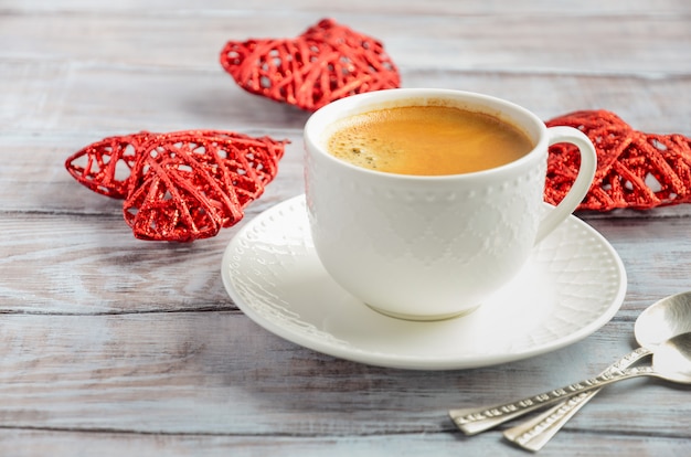 Tazza di caffè fresco di mattina su un fondo di legno. Concetto di San Valentino.