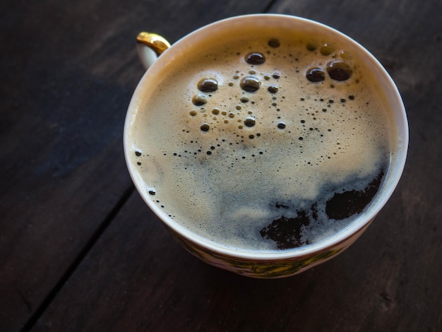 Tazza di caffè fresco sul fuoco selettivo di vista superiore del fondo di legno