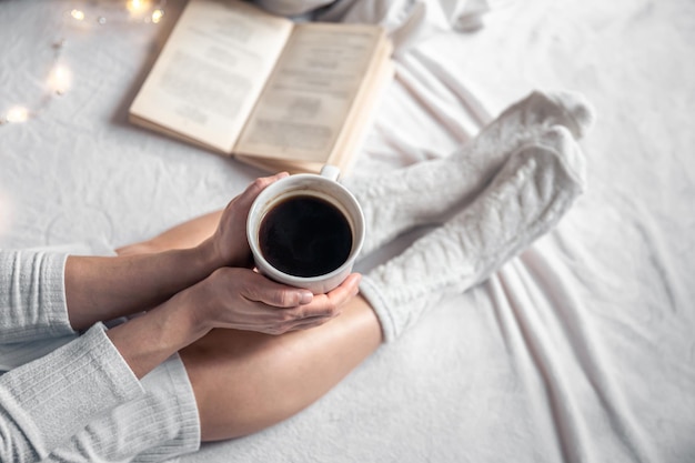 Tazza di caffè in mani femminili nella vista dall'alto del letto