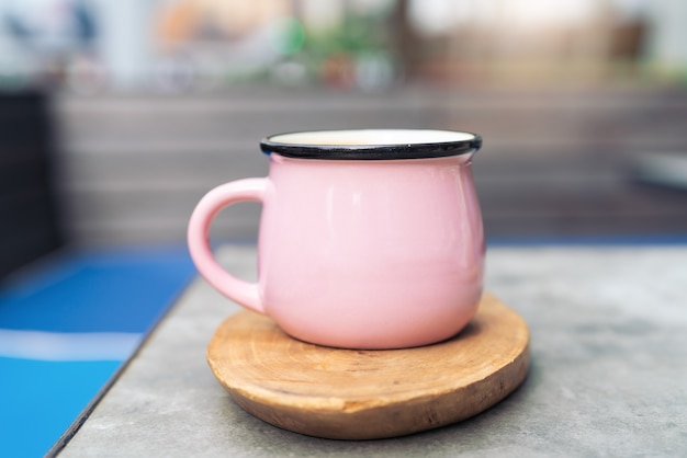 Tazza di caffè in vetro rosa sul piatto di legno