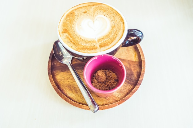 Tazza di caffè latte a forma di cuore su sfondo di legno vecchio alla luce del sole del mattino