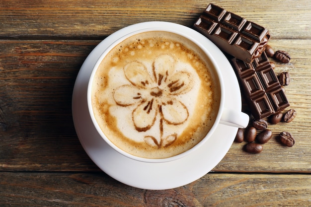 Tazza di caffè latte art con cereali e cioccolato su tavola di legno, vista dall'alto