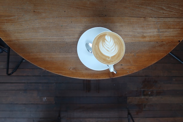 tazza di caffè latte art con cucchiaio e piastra sullo sfondo struttura arrotondata