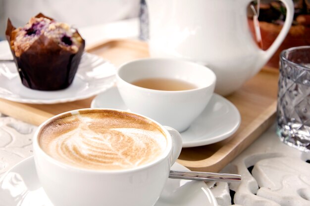 Tazza di caffè latte con tè e muffin. Caffè del mattino Tono bianco.