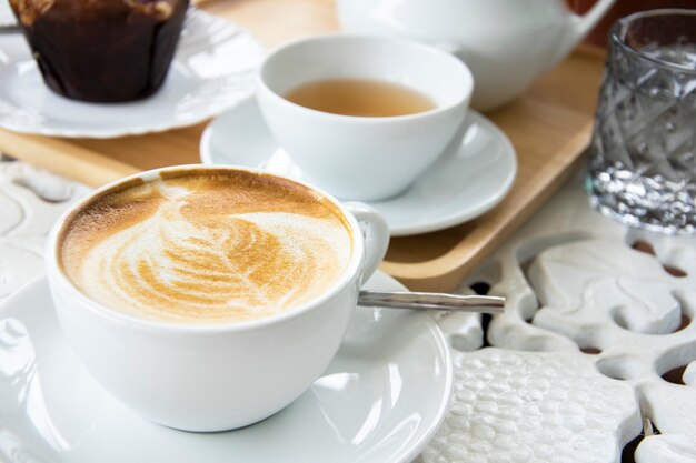 Tazza di caffè latte con tè e muffin. Caffè del mattino Tono bianco.