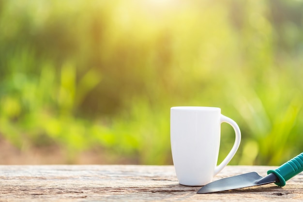 Tazza di caffè, libro e attrezzatura di giardino sulla tavola di legno con luce solare a tempo la mattina