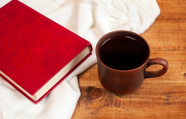 tazza di caffè, libro e plaid sul primo piano della tavola di legno