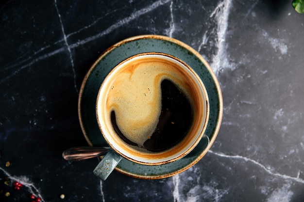 Tazza di caffè macinato fresco nero sul tavolo di marmo scuro