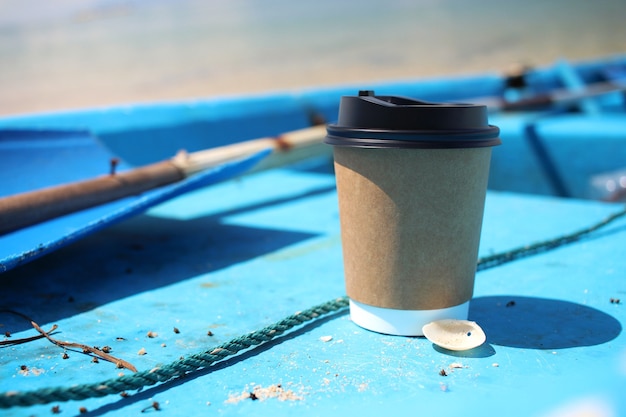 Tazza di caffè mattutino con guscio in barca blu con sfondo mare