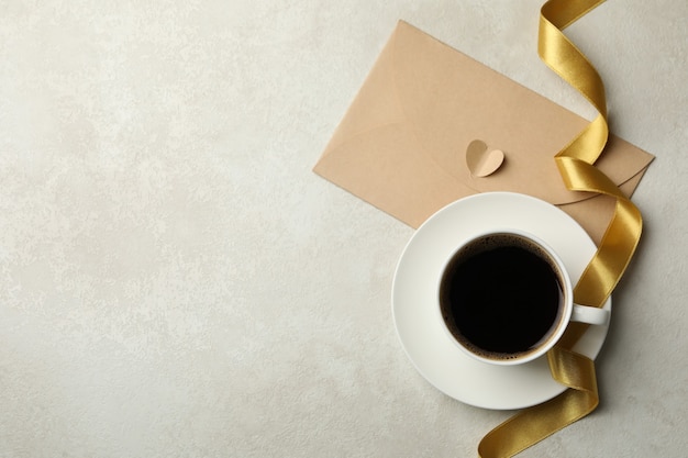 Tazza di caffè, nastro e busta su sfondo con texture