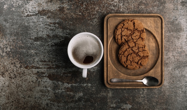 Tazza di caffè nero caldo sullo scrittorio di legno con i biscotti