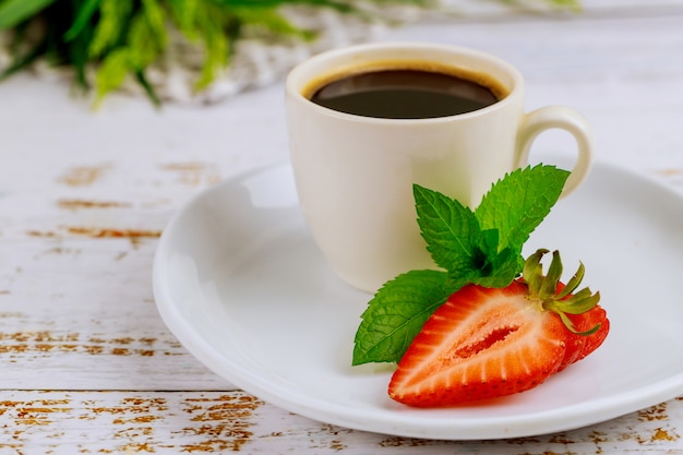 Tazza di caffè nero con cioccolato e fragola sulla tavola bianca