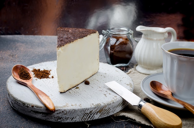 Tazza di caffè nero con un pezzo di formaggio morbido nel caffè macinato