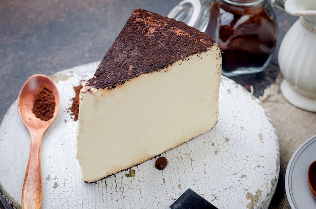 Tazza di caffè nero con un pezzo di formaggio morbido nel caffè macinato