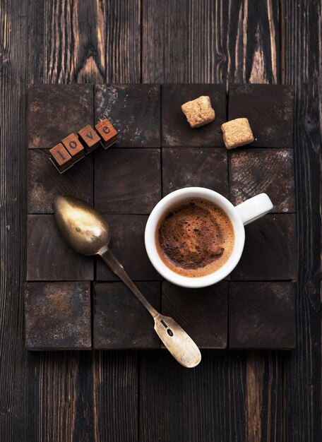 Tazza di caffè nero con zucchero su fondo di legno e testo d'amore, piatto