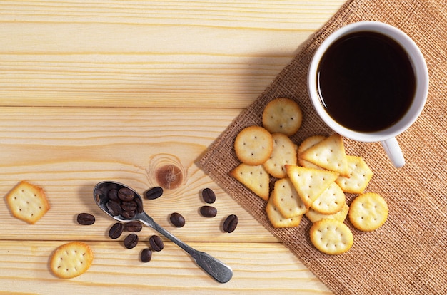 Tazza di caffè nero e cracker con sapore di formaggio per colazione su tavola di legno, vista dall'alto