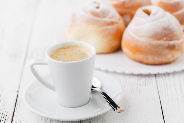 Tazza di caffè nero e panino dolce per la prima colazione, primo piano