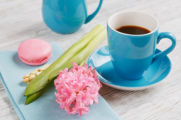 Tazza di caffè nero, fiori rosa e amaretti francesi